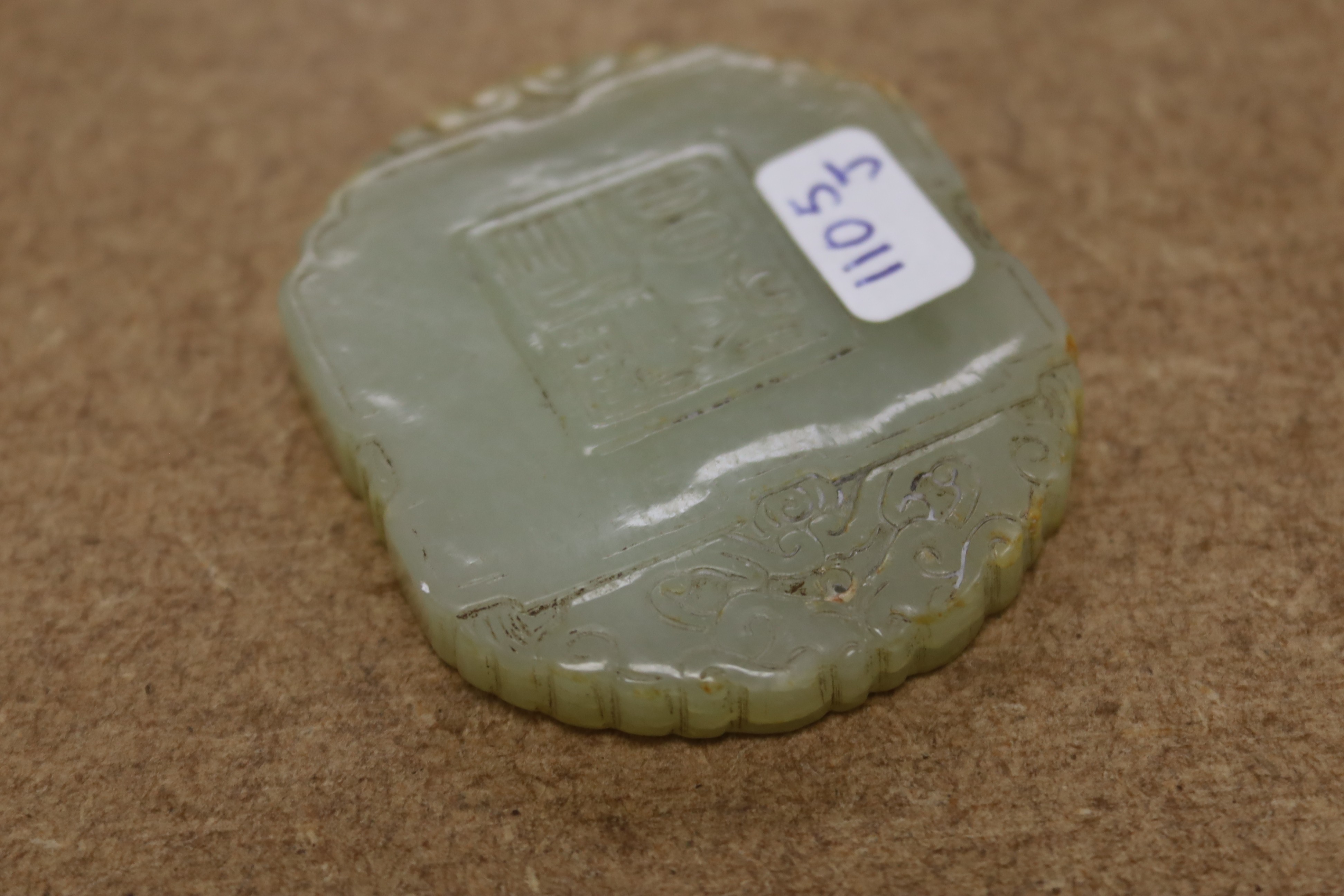 A Chinese pale celadon jade plaque, boy and bats, 5cm wide